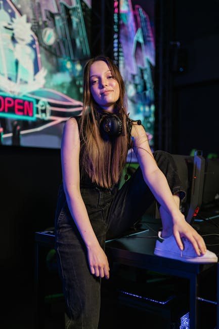 Woman in Black Tank Top and Black Denim Jeans Sitting on Black Computer Table